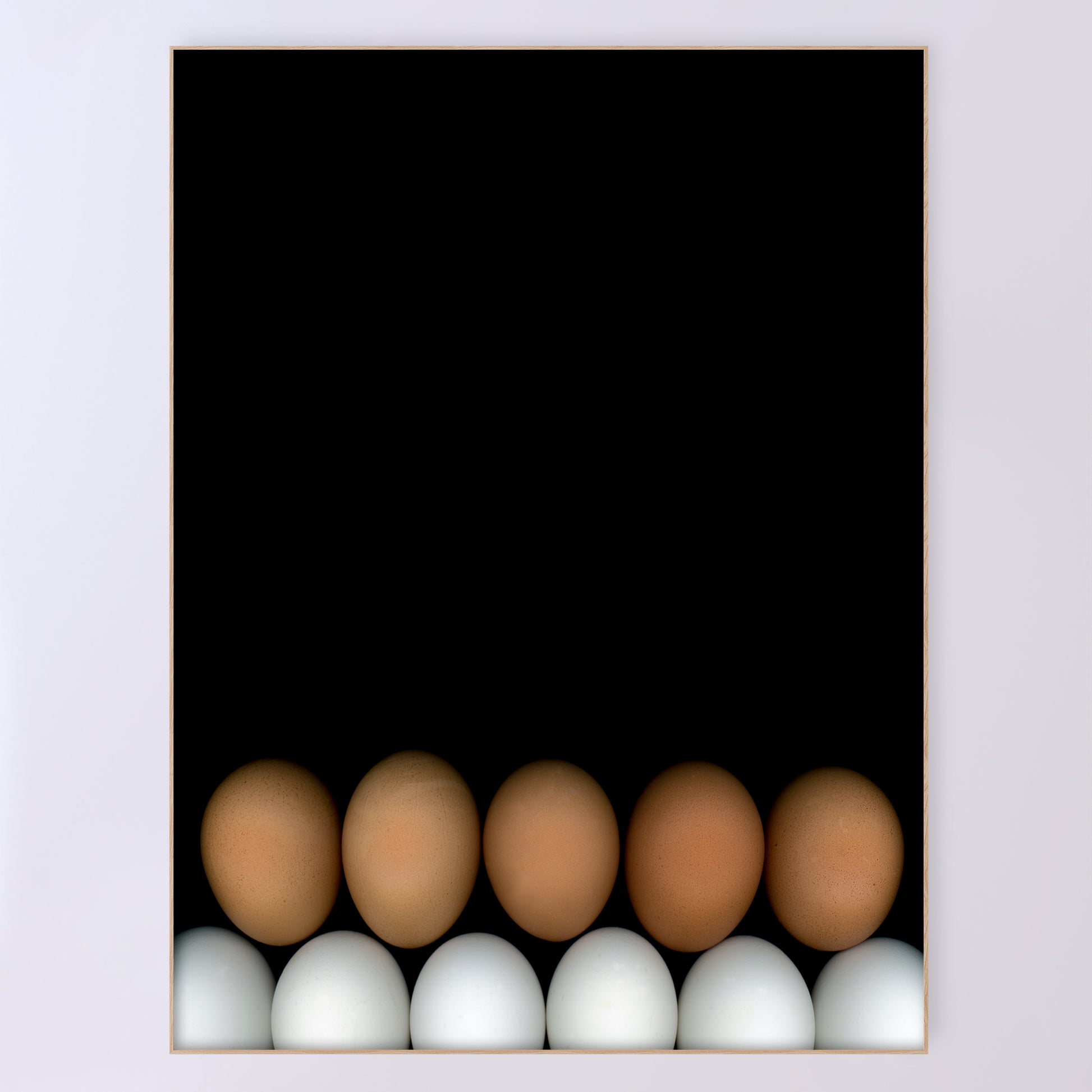 Two rows of chicken eggs one brown row and one white row on a black background in a light beige wood frame. Open edition print by Carmen Grenier. OE-355-5, 36x48 inches.